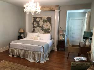 1 dormitorio con cama y lámpara de araña en Clevedale Historic Inn and Gardens, en Spartanburg