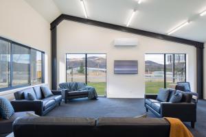 a waiting room with couches and a tv and windows at Harvest Park Studios Workers Accommodation in Cromwell