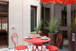 a red table and chairs on a patio with plants at Amazing apartment in Duomo in Milan