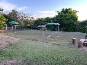 un parque infantil con sombrillas verdes en un campo en Chalé Dom Quixote, en São Pedro
