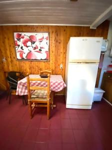 a kitchen with a table and a refrigerator at Torres Del Sur Cabañas & Hostal in Villarrica