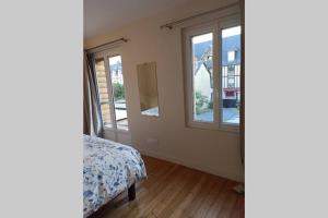 ein Schlafzimmer mit zwei Fenstern und einem Bett in einem Zimmer in der Unterkunft Villa N°5 in Blonville-sur-Mer