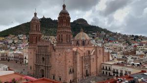 un grand bâtiment avec deux tours au sommet d'une ville dans l'établissement Santa Rita Hotel del Arte, à Zacatecas
