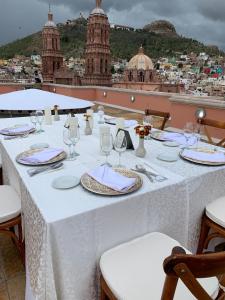 Ein weißer Tisch mit Gläsern und Servietten auf einem Balkon in der Unterkunft Santa Rita Hotel del Arte in Zacatecas