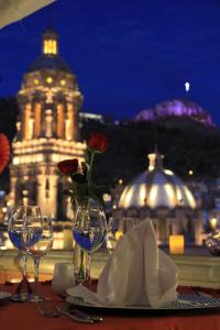 a table with wine glasses and a vase with a flower at Santa Rita Hotel del Arte in Zacatecas