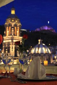 Santa Rita Hotel del Arte في زاكاتيكاس: طاولة مع كؤوس للنبيذ و مزهرية مع زهرة