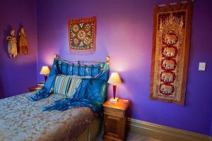ein Schlafzimmer mit lila Wänden, einem Bett und zwei Lampen in der Unterkunft Sea Breeze B & B in Napier