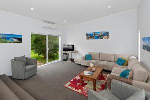 ein Wohnzimmer mit einem Sofa und einem Tisch in der Unterkunft Pohutukawa Peace - Mangawhai Holiday Home in Mangawhai