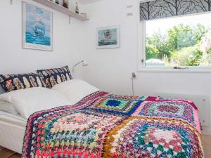 Three-Bedroom Holiday home in Glesborg 33 في Bønnerup: سرير مع بطانية كروشيه ملونة عليه