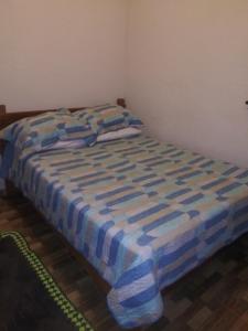 a bed with a blue and white blanket on it at Casa da Seriema em Lapinha da Serra in Santana do Riacho