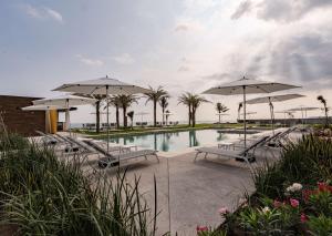 una piscina con ombrelloni e sedie e una piscina di Best Western Plus Riviera Veracruz a Veracruz