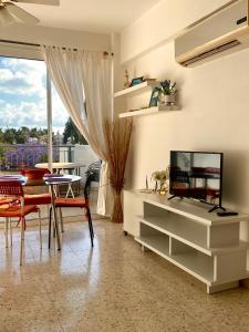 ein Wohnzimmer mit einem TV, einem Tisch und Stühlen in der Unterkunft Paradise Garden in Paphos City