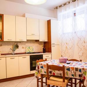 una cucina con mobili bianchi e un tavolo con sedie di Casa Mare Naxos Flat - Home Holiday a Giardini Naxos