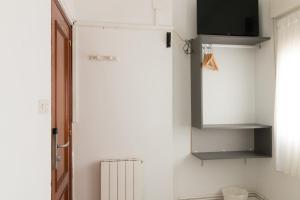 kuchnia z lodówką i telewizor na ścianie w obiekcie Pensión Arias w mieście Bilbao