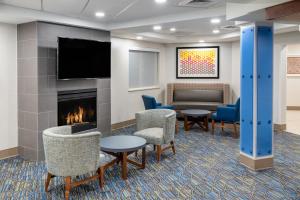 a lobby with a fireplace and chairs and a couch at Holiday Inn Express & Suites Colorado Springs-Airport, an IHG Hotel in Colorado Springs