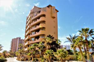 a tall building with palm trees in front of it at Bella Sirena Luxury Resort 205-D in Puerto Peñasco