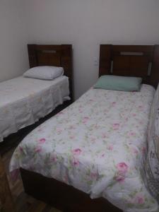a bedroom with two beds with flowers on the sheets at Casa da Seriema em Lapinha da Serra in Santana do Riacho