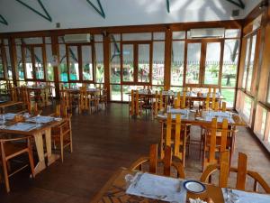 a restaurant with wooden tables and chairs and windows at KTDC Water Scapes in Kumarakom