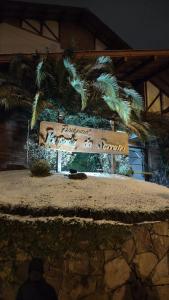 a sign in front of a building with palm trees at Residencial Pousada do Serrano in Gramado