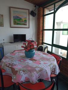 a table with a table cloth with a vase of flowers on it at Quartos Masculino - Romas House in Itu