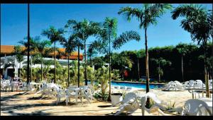 um grupo de cadeiras brancas e uma piscina com palmeiras em Fiori Caldas Novas - 245 em Caldas Novas