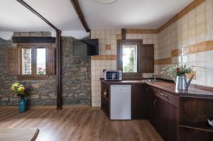 a kitchen with a refrigerator and a tv on the wall at La Borda de Pastores in Sabiñánigo