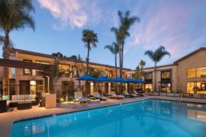 a swimming pool in front of a building with palm trees at The Cove Hotel in Long Beach