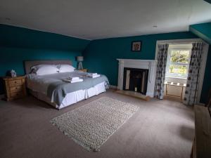 a blue bedroom with a bed and a fireplace at Rottal Farmhouse in Millton of Clova