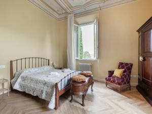um quarto com uma cama, uma cadeira e uma janela em Belvilla by OYO Villa Rose em Cecina