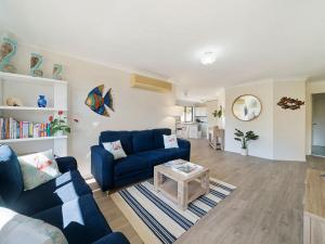 a living room with a blue couch and a table at Escape to Janeli by Experience Jervis Bay in Vincentia