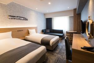 a hotel room with two beds and a desk at Hotel Torifito Otaru Canal in Otaru