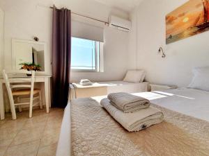 a bedroom with two beds and a desk and a window at Eva Ivoni apartments in Amoudara Herakliou