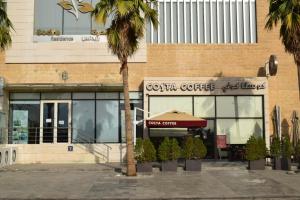 a store with a palm tree in front of a building at Sedra Residence in Kuwait