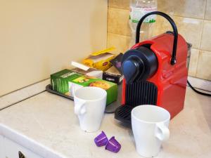 a red blender sitting on top of a counter with cups at Golosievo residence 60m2 in Kyiv