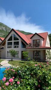 Villa Coast of Montenegro في بار: منزل بسقف احمر وبعض الزهور