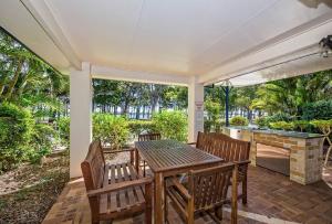 an outdoor patio with a table and chairs and a fireplace at Sandy Toes in Bellara