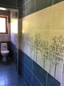 W łazience znajduje się niebieska ściana wyłożona kafelkami z namalowanymi drzewami. w obiekcie Villa Coast of Montenegro w Barze
