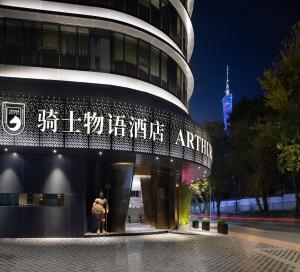 um casal à porta de um edifício à noite em 广州塔骑士物语酒店-Arthur Hotel Canton Tower Guangzhou em Guangzhou