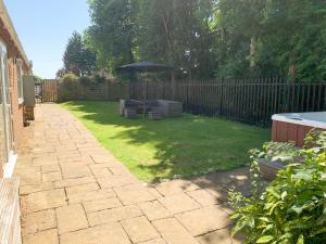 a backyard with an umbrella and chairs and a lawn at Mill Lodge in Brisley +4 photos
