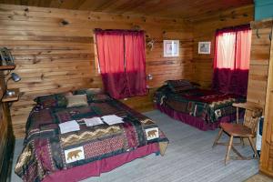 1 dormitorio con 2 camas en una cabaña de madera en lake guest ranch en Devils Tower