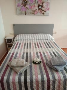ein Bett mit zwei Kissen und einer Blume darauf in der Unterkunft Almudena Estudio in Torrevieja