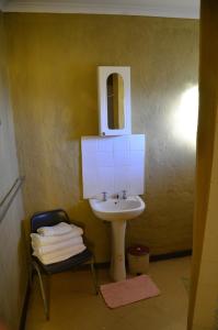 ein Badezimmer mit einem Waschbecken, einem Spiegel und einem Stuhl in der Unterkunft Bama Lodge in Ohrigstad