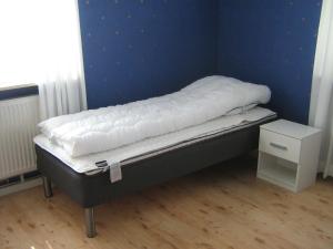 a bed in a room with a blue wall at Ulricehamn Nilsagården in Ulricehamn