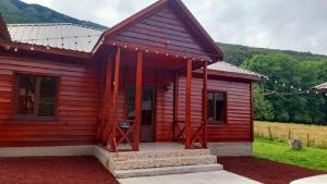 a small red cabin with a porch and a porch at Guest House Ushba Gate in Mestia