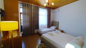 Cette petite chambre comprend 2 lits et une fenêtre. dans l'établissement A&Fabio Guesthouse, à Gjirokastër