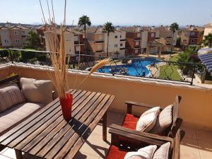 a balcony with a table and chairs and a swimming pool at Dúplex Águeda Altaona Golf in Murcia