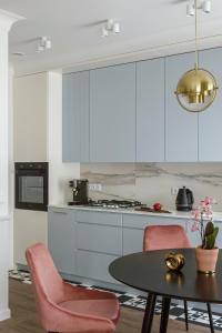 a kitchen with white cabinets and a table and pink chairs at Flav Apartment in Kraków