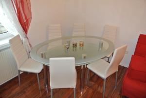 a glass dining room table with white chairs and a red couch at Apartment Paradies - U1 Station altes Landgut in Vienna