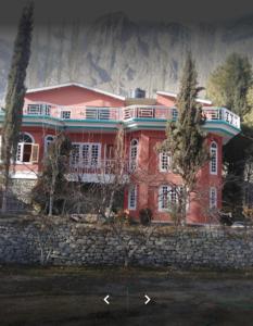 duży czerwony dom z balkonem na kamiennej ścianie w obiekcie Arcadian Inn Hotel w mieście Gilgit