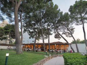 a building with people sitting at tables in a park at BQ Belvedere Hotel in Palma de Mallorca